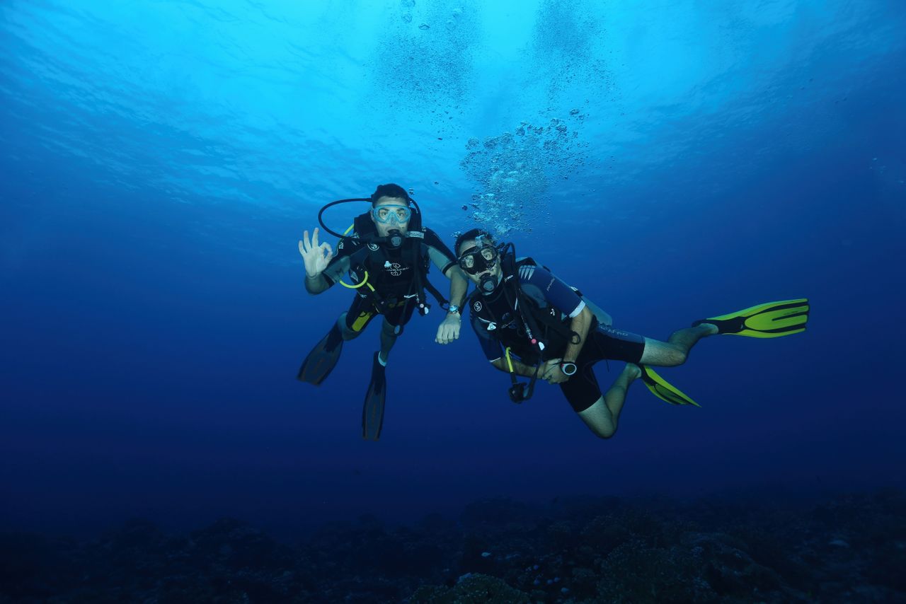 Crafting Captivating Headlines: Your awesome post title goes here Two scuba divers with gear exploring the deep blue ocean, captured under natural light.