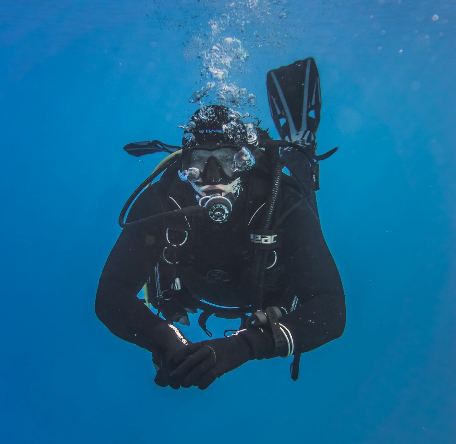 Underwater view of a scuba diver exploring the ocean depths, surrounded by a tranquil blue ambiance.